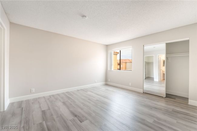 Unfurnished bedroom featuring a textured ceiling, light wood finished floors, and a closet | Image 16