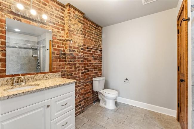 Bathroom featuring brick wall, vanity, a shower stall, and tile patterned floors | Image 14