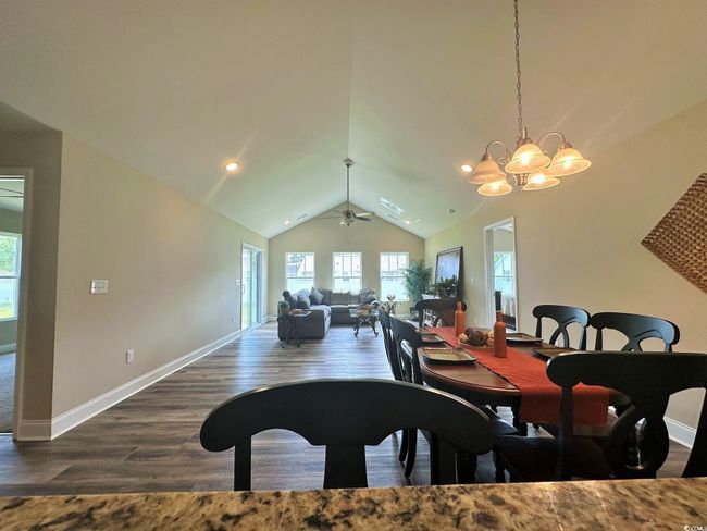 Dining area with baseboards, recessed lighting, lofted ceiling, ceiling fan with notable chandelier, and wood finished floors | Image 5
