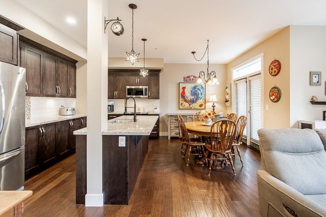 Kitchen with appliances with stainless steel finishes, dark brown cabinetry, a sink, dark wood-type flooring, and tasteful backsplash | Image 5
