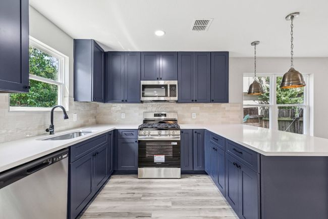 Kitchen featuring appliances with stainless steel finishes, a sink, a peninsula, light countertops, and recessed lighting | Image 4