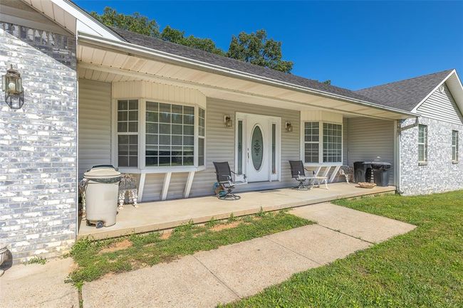 Doorway to property featuring covered porch and roof with shingles | Image 5