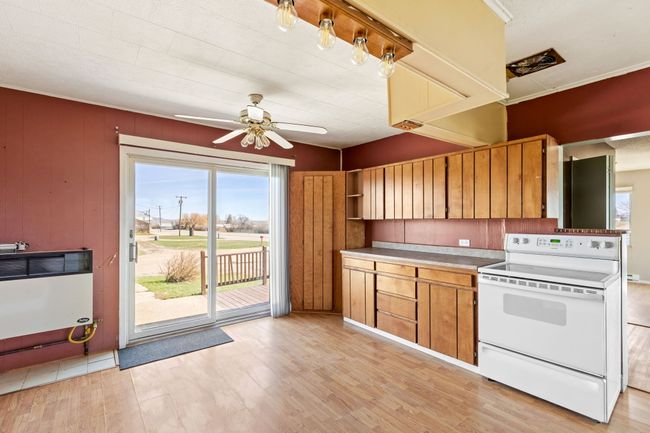Kitchen featuring light wood-type flooring, a ceiling fan, brown cabinetry, and white electric range | Image 20
