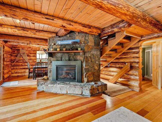 Unfurnished living room with wood-type flooring, stairs, beamed ceiling, and a stone fireplace | Image 15