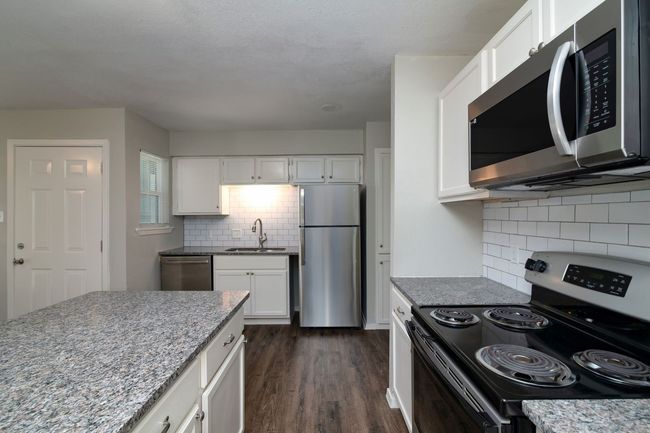 Kitchen with stainless steel appliances, backsplash, white cabinets, and a sink | Image 5