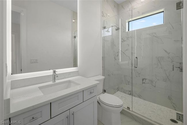 Second Bedroom Bath featuring Quartz vanity, backlit frameless anit-fog mirror, frameless shower enclosure and all custom tile work throughout. | Image 13