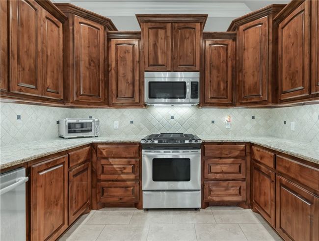 Kitchen with appliances with stainless steel finishes, light stone counters, and backsplash | Image 14
