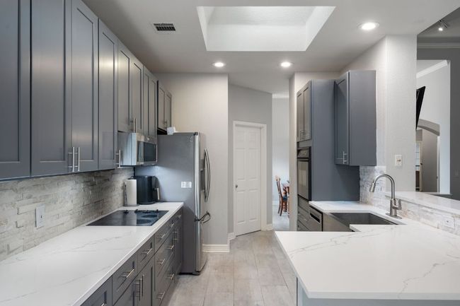 Kitchen featuring tasteful backsplash, visible vents, a sink, and black appliances | Image 16