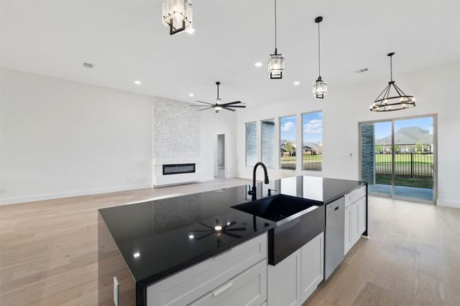 Kitchen featuring stainless steel dishwasher, a sink, dark countertops, light wood-style flooring, and a fireplace | Image 26