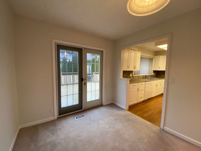 Doorway to outside featuring carpet, visible vents, baseboards, and a sink | Image 6