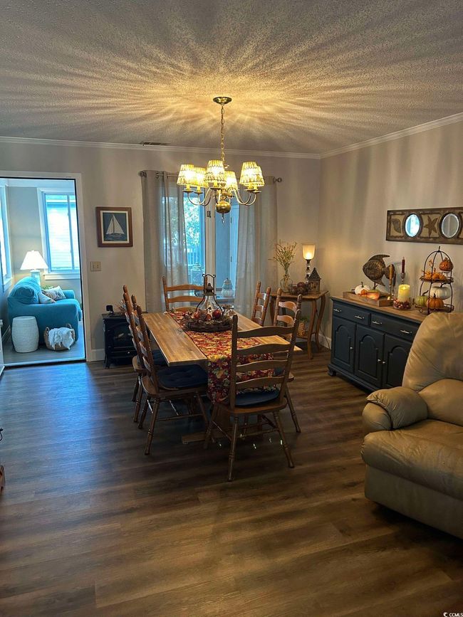 Dining room featuring a chandelier, crown molding, dark wood-style floors, and a textured ceiling | Image 4