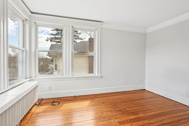 Unfurnished room featuring crown molding, radiator heating unit, light wood finished floors, and baseboards | Image 21