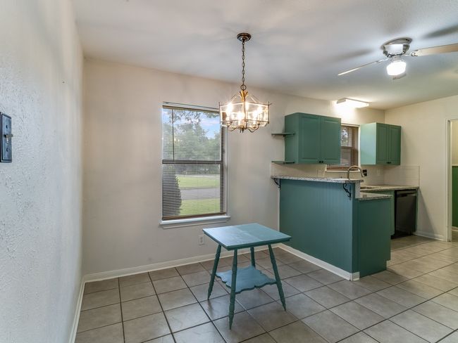 Kitchen with green cabinets, dishwasher, light tile patterned floors, a peninsula, and a chandelier | Image 8