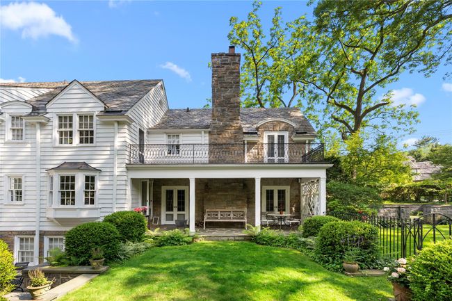 Rear view of property featuring french doors, a balcony, a high end roof, a chimney, and stone siding | Image 38