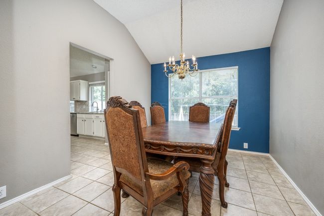 Dining space with a chandelier, light tile patterned floors, and vaulted ceiling | Image 11