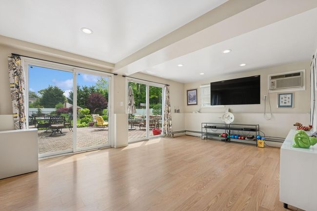 Living room with an AC wall unit, recessed lighting, wood finished floors, and baseboard heating | Image 17