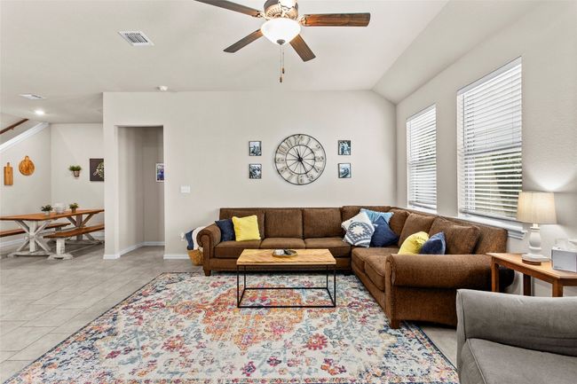 Living room featuring ceiling fan, light tile patterned floors, vaulted ceiling, and stairway | Image 10