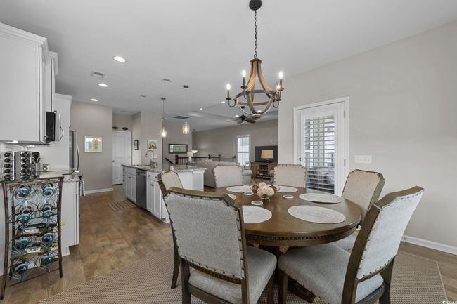 Dining room with dark wood-type flooring, a chandelier, baseboards, and recessed lighting | Image 9