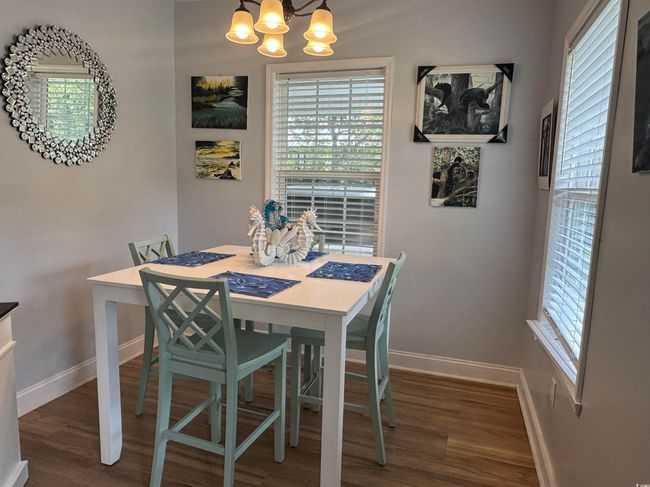 Dining area featuring baseboards, a chandelier, and wood finished floors | Image 4