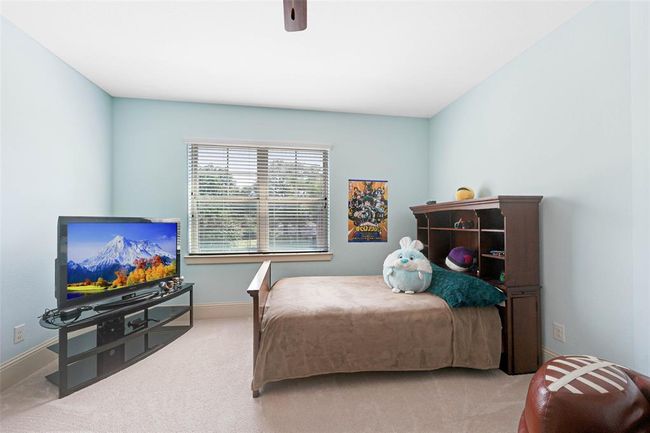 Comfortable secondary bedroom with soft carpet, light blue walls, and a large window offering natural light and outdoor views. Ideal as a guest room, kid’s room, or flex space. | Image 34
