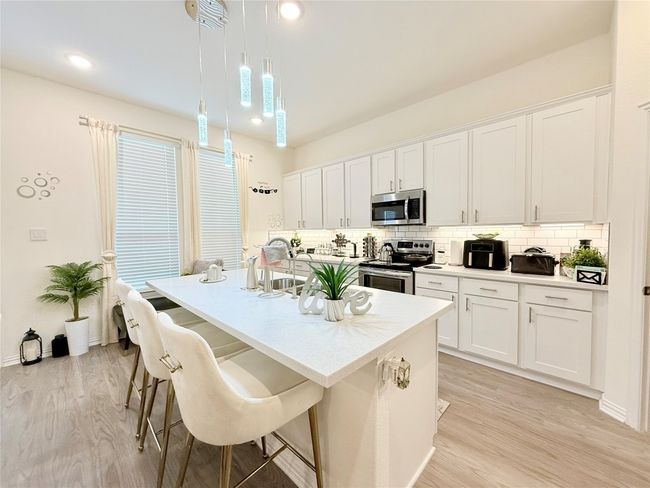 Kitchen with stainless steel appliances, tasteful backsplash, light wood-style flooring, light countertops, and recessed lighting | Image 9