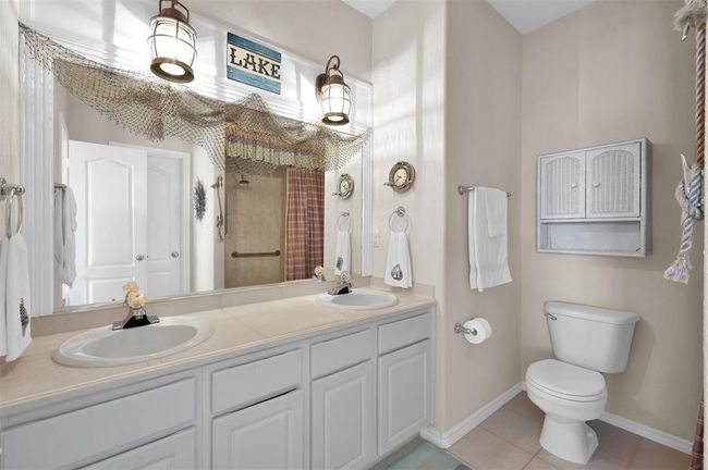 Primary bath features double vanities and nautical light fixtures. | Image 17