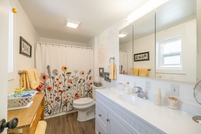 Bathroom featuring wood finished floors, vanity, toilet, and curtained shower | Image 12