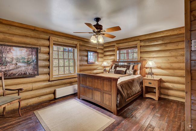 Bedroom featuring radiator heating unit, dark wood-style floors, and rustic walls | Image 17