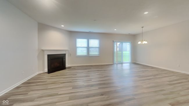 unfurnished living room with recessed lighting, an inviting chandelier, light wood-style floors, a fireplace, and baseboards | Image 4