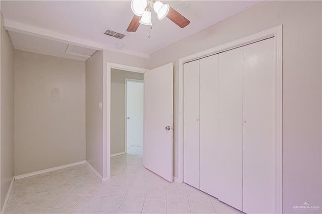 Unfurnished bedroom with light tile patterned floors, a closet, a ceiling fan, visible vents, and baseboards | Image 21