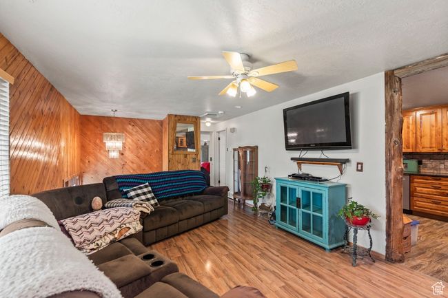 Living area featuring wooden walls, light wood-type flooring, and a ceiling fan | Image 6