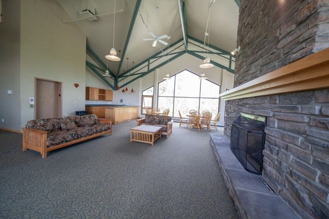 Living area with high vaulted ceiling, carpet flooring, ceiling fan, and a fireplace | Image 23