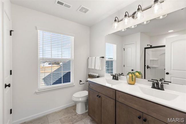 Full bathroom with baseboards, double vanity, toilet, and a shower with door | Image 18