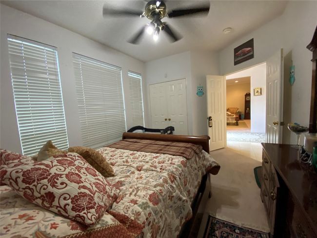 Bedroom featuring ceiling fan, a closet, and light carpet | Image 32
