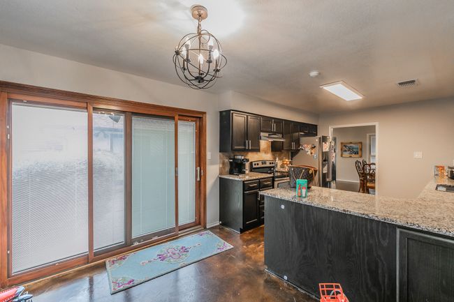 Unit 4904 Kitchen with appliances with stainless steel finishes, hanging light fixtures, tasteful backsplash, light stone countertops, and kitchen peninsula | Image 31