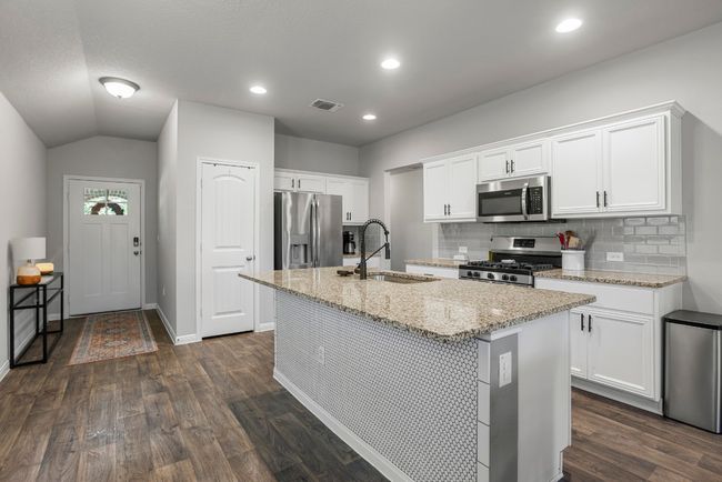 Kitchen featuring appliances with stainless steel finishes, a kitchen island with sink, dark wood-type flooring, backsplash, and recessed lighting | Image 7