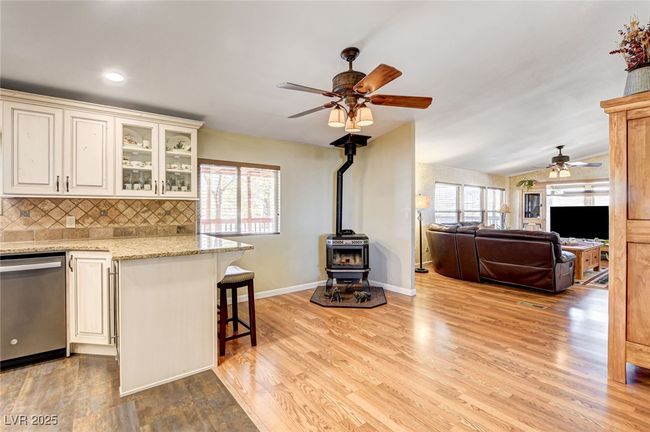 Kitchen with dishwasher, a ceiling fan, a wood stove, decorative backsplash, and a breakfast bar | Image 18