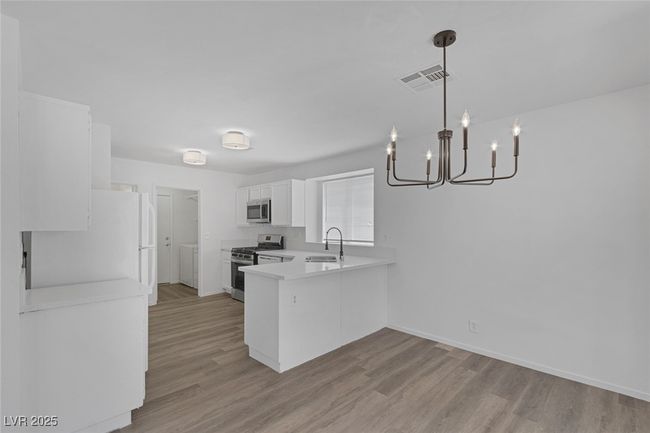 Kitchen featuring stainless steel appliances, a chandelier, a peninsula, light wood-type flooring, and light countertops | Image 8