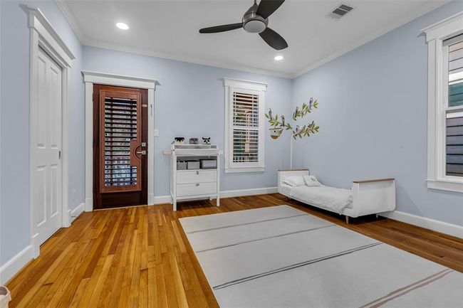 This secondary bedroom features a cozy space with light grey walls, hardwood floors, and a ceiling fan. It opens to the second floor wraparound porch. It also sharea a Jack N Jill bathroom with bedroom No. 3. | Image 23