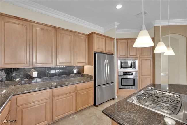 Kitchen featuring backsplash, ornamental molding, dark stone countertops, and appliances with stainless steel finishes | Image 16