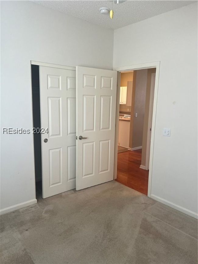 Unfurnished bedroom featuring a textured ceiling, carpet flooring, and a closet | Image 23