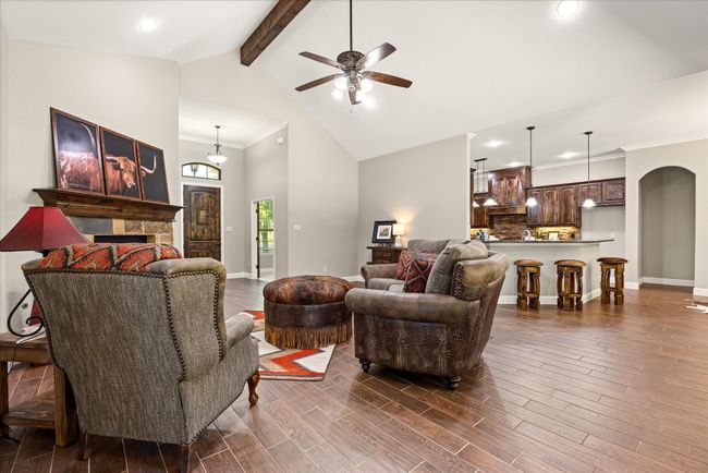 Living room featuring beam ceiling, high vaulted ceiling, a ceiling fan, crown molding, and dark wood finished floors | Image 5