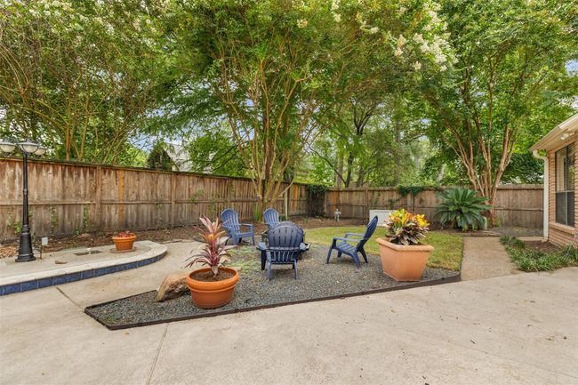 Tucked beside the pool, a versatile outdoor area offers the perfect balance of openness and privacy. Whether you envision relaxed evenings around a fire feature, a quiet seating nook, or a play space, this inviting green space adds even more function to the backyard retreat. | Image 38