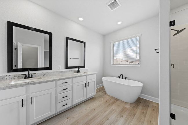 Master bathroom includes granite countertop, elongated mirror, and dual-vanity sinks. Relax in the large soaking tub or enjoy the spacious, standing shower. | Image 8