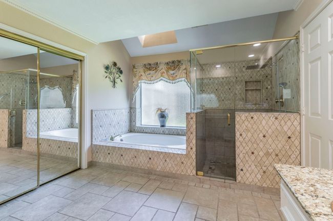 Full bathroom featuring vanity, a bath, a shower stall, crown molding, and stone tile floors | Image 15