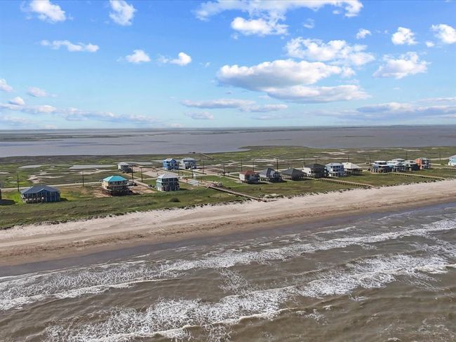 This wide aerial reveals the true scope of your future view. With no houses between you and the water, 5002 Blue Water Hwy offers a rare, unobstructed slice of beachfront paradise—on one of the few stable beaches remaining along the Texas Gulf Coast. | Image 17