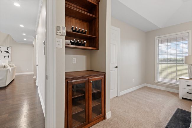 Primary bedroom showing the built in cabinets, perfect for your in room coffee station. Living room to the left. Large window bringing in natural light and the closed door opens to the office space by the front door. New carpet has never had furniture on it except for the staging furniture now. | Image 22