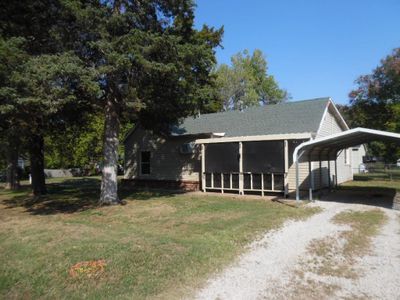 View of home's exterior with a sunroom, a carport, and a yard | Image 1