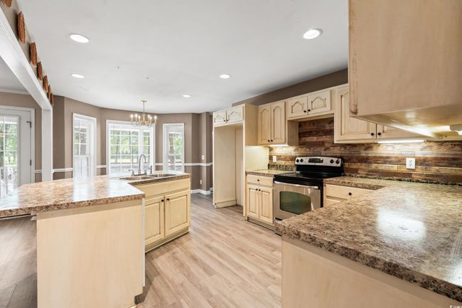 Kitchen with stainless steel range with electric cooktop, decorative backsplash, light wood-style floors, recessed lighting, and a chandelier | Image 28
