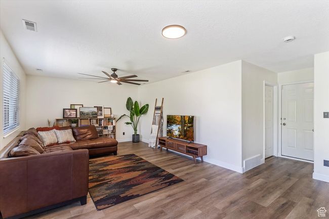Living area featuring wood finished floors, a ceiling fan, and baseboards | Image 10